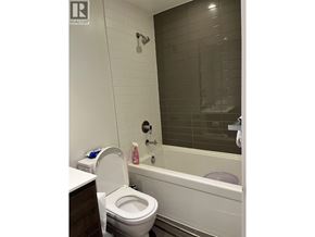 Burnaby apartment for rent - A white toilet sits next to a bathtub in a bathroom.