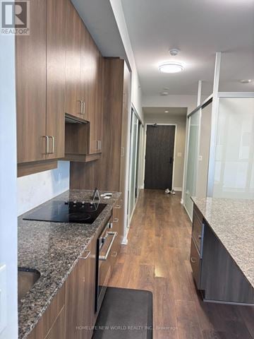 Toronto (Kensington-Chinatown) condo for rent - A kitchen with wooden cabinets and a black countertop.
