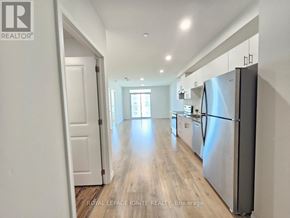 Guelph (Willow West/Sugarbush/West Acres) condo for rent - A kitchen with a refrigerator on the right side and a door on the left.