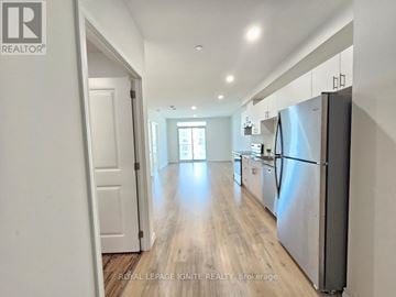 Guelph (Willow West/Sugarbush/West Acres) condo for rent - A kitchen with a refrigerator on the right side and a door on the left.