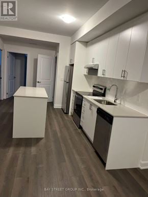 Oakville (Jm Joshua Meadows) condo for rent - A kitchen with white cabinets and a wooden floor.