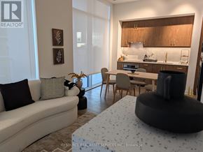 Toronto (Niagara) condo for rent - A modern living room with a grey sofa and a black ottoman.