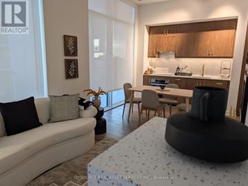 Toronto (Niagara) condo for rent - A modern living room with a grey sofa and a black ottoman.