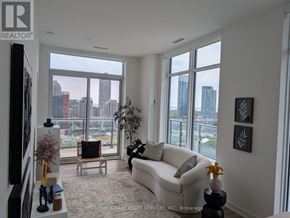 Toronto (Niagara) condo for rent - A living room with a couch, a chair, a television, and a large window with a view of the city.