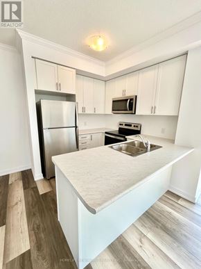 Hamilton (Waterdown) condo for rent - A kitchen with white cabinets and a wooden floor.