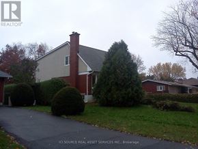 Ottawa apartment for rent - A house with a red brick chimney is surrounded by green bushes and trees.