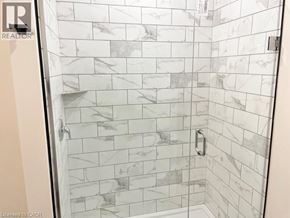 Simcoe apartment for rent - A shower with a marble tile wall and a glass door.