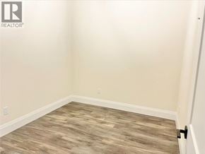Simcoe apartment for rent - A room with a wooden floor and a Realty logo on the wall.