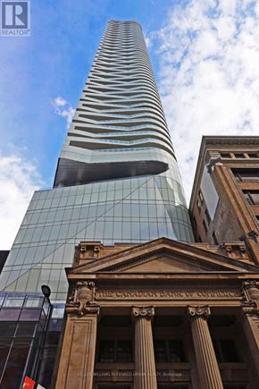 Toronto (Church-Yonge Corridor) condo for rent - A tall glass building stands next to a building with columns.