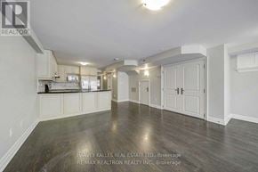 Toronto (Forest Hill South) triplex for rent - A spacious room with wooden flooring and white walls, featuring a kitchen area with white cabinets and appliances.