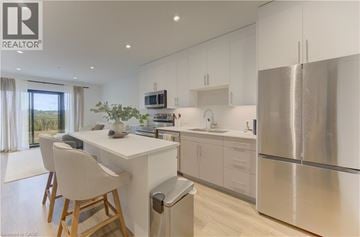Kitchener condo for rent - A modern kitchen with white cabinets and stainless steel appliances.