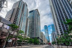 Toronto (Bay Street Corridor) condo for rent - A city street with tall buildings on either side and a red car driving down the road.