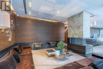 Toronto (Bay Street Corridor) condo for rent - A modern living room with a brown sofa and a glass table.