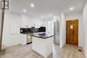 Toronto (Blake-Jones) townhouse for rent - A kitchen with white cabinets and a black countertop.