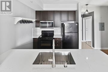 Burlington (Uptown) condo for rent - A modern kitchen with a stainless steel refrigerator and a marble countertop.
