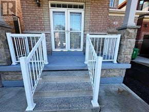 Brampton (Madoc) apartment for rent - A brick house with a white railing and steps leading to a glass door.