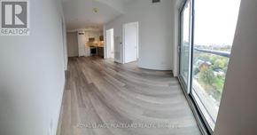 Toronto (Kensington-Chinatown) condo for rent - A spacious room with wooden flooring and large windows overlooking a cityscape.