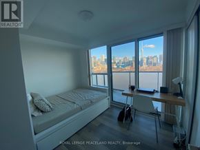Toronto (Kensington-Chinatown) condo for rent - A bedroom with a bed, desk, and chair with a view of the city.