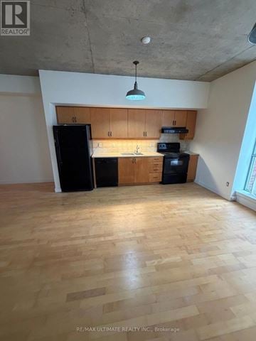 Toronto (Dovercourt-Wallace Emerson-Junction) condo for rent - A kitchen with wooden floors and a black refrigerator.