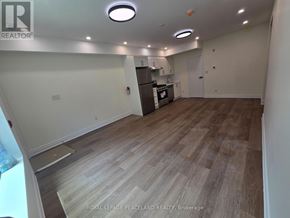 Toronto (University) apartment for rent - A spacious room with wooden flooring and a kitchen area in the background.