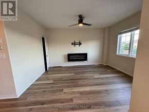 Hamilton (Stoney Creek Mountain) townhouse for rent - A spacious room with wooden flooring and a fireplace.