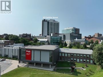 St. Catharines (Downtown) condo for rent - A building with a Brock sign on it is in the foreground of a city scene.