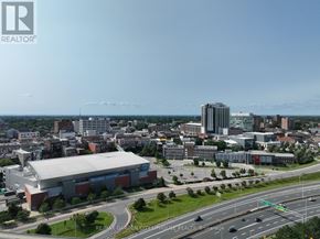 St. Catharines (Downtown) condo for rent - A cityscape with a large building in the foreground and a highway in the background.
