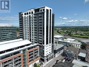St. Catharines (Downtown) condo for rent - A tall building with a glass facade stands in the foreground of a cityscape.