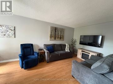 Milton (Co Coates) townhouse for rent - A living room with a grey couch, blue chair, and a television mounted on the wall.