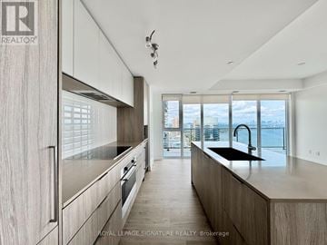 Toronto (Mimico) condo for rent - A modern kitchen with wooden cabinets and a view of the city.