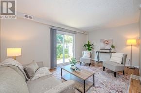 Guelph (Junction/Onward Willow) townhouse for rent - A well-lit living room with a grey sofa, a coffee table, and a large window.