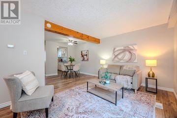 Guelph (Junction/Onward Willow) townhouse for rent - A living room with a grey sofa, a grey armchair, a coffee table and a rug.