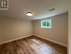 Guelph (Riverside Park) apartment for rent - A room with wooden flooring and a window showing greenery outside.