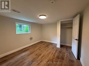 Guelph (Riverside Park) apartment for rent - A room with wooden flooring and a window showing greenery outside.