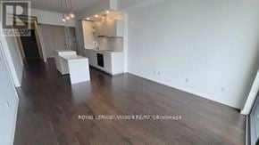 Toronto (Waterfront Communities) condo for rent - A spacious room with wooden floors and white walls, featuring a kitchenette with a sink and a refrigerator.