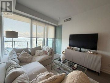 Toronto (Kensington-Chinatown) condo for rent - A living room with a large couch and a flat screen TV.