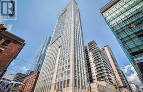 Toronto (Church-Yonge Corridor) condo for rent - A tall building with many windows stands in the middle of a city street.