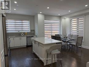 Brampton (Bram West) apartment for rent - A kitchen with white cabinets and a dining table with chairs.
