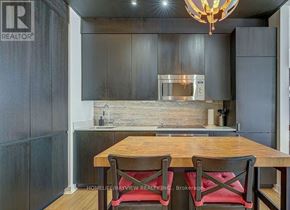 Toronto (Waterfront Communities) condo for rent - A modern kitchen with a wooden table and chairs.