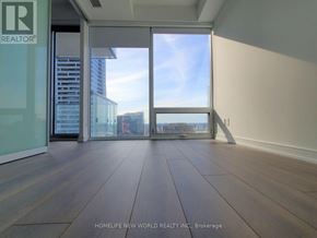 Toronto (Church-Yonge Corridor) condo for rent - A room with wooden flooring and large windows overlooking a cityscape.