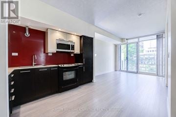 Toronto (Waterfront Communities) condo for rent - A modern kitchen with black cabinets and a red accent wall.