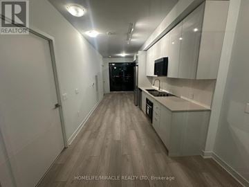 Vaughan (Concord) condo for rent - A kitchen with white cabinets and a wooden floor.
