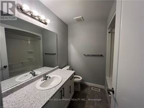 Hamilton townhouse for rent - A bathroom with a sink, mirror, and toilet.