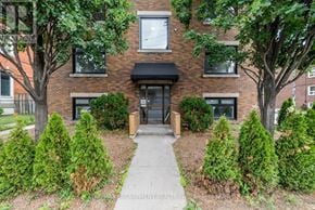 Hamilton (Stinson) multi-family for rent - A brick building with a black awning and a small garden in front.