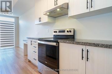 Burlington (Tyandaga) townhouse for rent - A modern kitchen with white cabinets and a black oven.