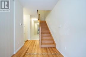 Burlington (Tyandaga) townhouse for rent - A wooden staircase leads up to a landing in a white room.