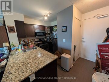 Toronto (Dovercourt-Wallace Emerson-Junction) condo for rent - A kitchen with granite countertops and a sign for RE/MAX Success Realty in the background.