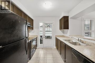 Milton (Wi Willmott) townhouse for rent - A kitchen with a black refrigerator and brown cabinets.