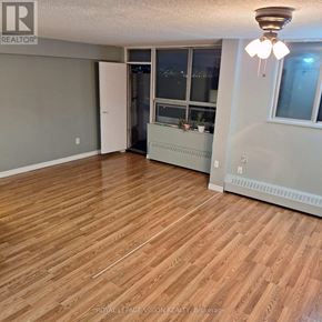 Toronto (Yorkdale-Glen Park) condo for rent - A room with wooden flooring and a window overlooking a cityscape.