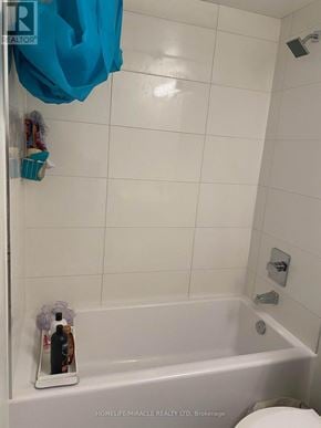 Toronto (Church-Yonge Corridor) condo for rent - A white tiled bathroom with a blue towel hanging on the shower door.
